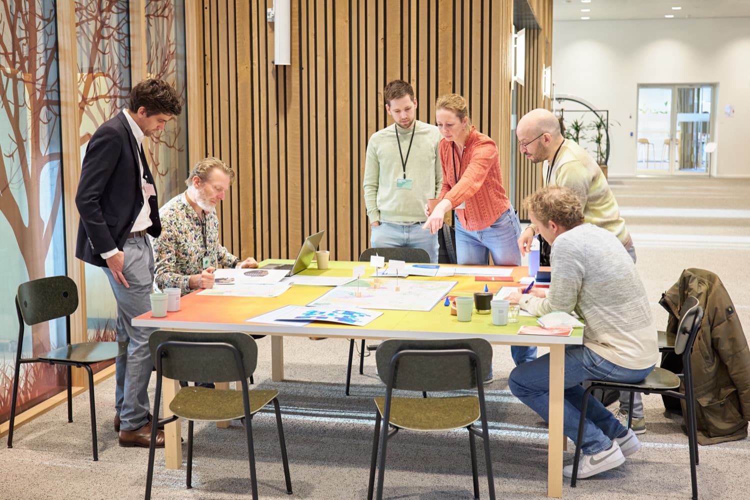 Deelnemers staan rond de speeltafel tijdens een serious-game-sessie